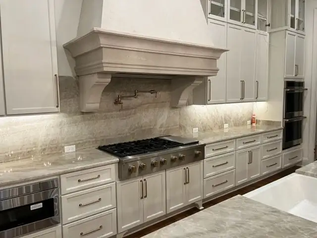 Kitchen with granite countertops by Collierville stone fabricator C&M Cabinets and Granite, with a cased range hood, tile backsplash and gas cooktop