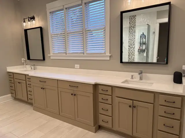 Double bathroom vanity with greige shaker cabinets, a white quartz top, two sinks and black-framed mirrors