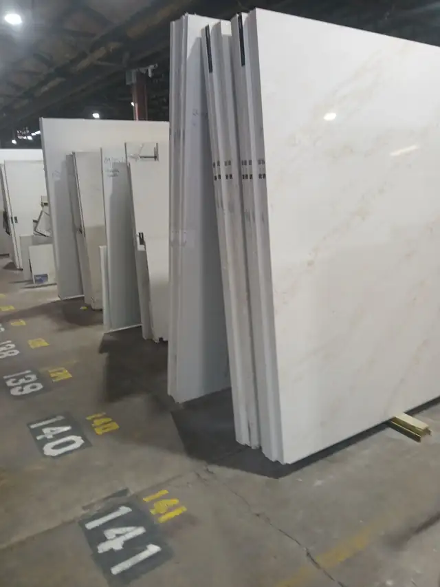 Rows of white veined countertop slabs lined up inside the C&M warehouse