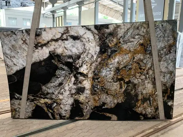 Exotic granite slab with black, white and gold swirls standing in the C&M slab yard